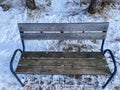 An empty wooden bench stands on the street in winter Royalty Free Stock Photo