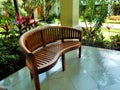 Empty wooden bench in tropical garden, outdoor furniture. Relax and rest concept. Patio design Royalty Free Stock Photo