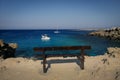 Empty wooden bench with a view to the sea at Blue Lagoon, Cape Greco, Cyprus. Royalty Free Stock Photo