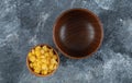 An empty wooden bowl with small bowl of popcorn seeds
