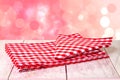 Empty wooden bright desk table with red checkered tablecloth over abstract blurred bright background. Template for your food and