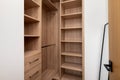 an empty wooden closet with a walk in closet space and a book shelf Royalty Free Stock Photo