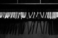 Empty wooden clothes hangers in empty black cloakroom, casting deep shadows. Royalty Free Stock Photo