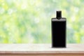 Black plastic bottle on wooden countertop on blurred spring background with bokeh