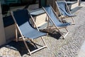 Empty wooden deck chairs near the cafe in summer. Tables and deckchairs at sidewalk cafe. Touristic setting, cafe table, sidewalk Royalty Free Stock Photo