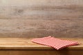 Empty wooden deck table with checked red tablecloth over wooden wall background for product montage