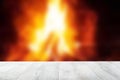 Empty wooden deck table over abstract blurred fireplace with blazing flames at night. Template for your product display montage. Royalty Free Stock Photo