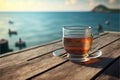 Empty wooden deck table over ocean background with glass cup of tea and saucer on wooden table, relaxing drink, generated ai