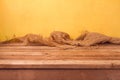 Empty wooden deck table and sackcloth over yellow wall background for product montage Royalty Free Stock Photo