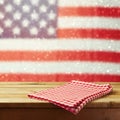 Empty wooden deck table with tablecloth over USA flag bokeh background. 4th of July celebration picnic background. Royalty Free Stock Photo