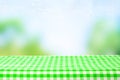 Empty wooden desk table with green checkered tablecloth over abstract bright light blue green spring or summer background. Royalty Free Stock Photo