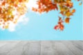 Empty wooden desk table over abstract blurred light blue sky and colorful autumn background with leaves. Template for your food Royalty Free Stock Photo