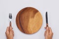 Empty wooden dish with knife and fork in hands. Top view Royalty Free Stock Photo