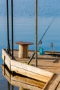 Empty wooden fishing pier with rods, table and bait. Beautiful reflection in a water Royalty Free Stock Photo