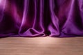 Empty wooden floor with Elegant wavy purple satin cloth curtains, defocused in the background Royalty Free Stock Photo