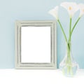 Empty wooden frame and flowers in vase on table on blue background. mock up Royalty Free Stock Photo