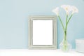 Empty wooden frame and flowers in vase on table on blue background. mock up Royalty Free Stock Photo