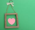 Empty wooden frame for painting with a pink heart lies on a green background Royalty Free Stock Photo