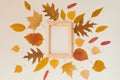 An empty wooden frame surrounded by yellow fallen leaves on a beige background. Autumn fla lay Royalty Free Stock Photo