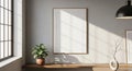 Empty wooden framed poster hanging on a light grey wall with bright sunlight casting shadows from a window and a Royalty Free Stock Photo