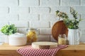 Empty wooden log on kitchen table with food jars and plants over white brick wall background. Kitchen mock up for design and Royalty Free Stock Photo