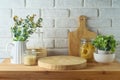 Empty wooden log on kitchen table with food jars and plants over white brick wall background. Kitchen mock up for design and Royalty Free Stock Photo