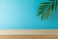 Empty wooden table with palm tree leaf over blue background . Summer mock up for design and product display