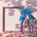 Empty wooden photo frame, blue chrysanthemums in vases, shapes in the form of hearts are on a light wooden background. Royalty Free Stock Photo