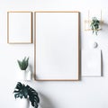 Empty wooden picture frame mockup. Golden vase with plant on white table. White wall background. Elegant working space. Royalty Free Stock Photo