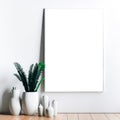 Empty wooden picture frame mockup. Golden vase with plant on white table. White wall background. Elegant working space. Royalty Free Stock Photo