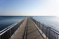 Empty wooden pier over blue sea with clear sky background. Royalty Free Stock Photo