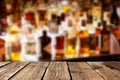 Empty wooden planks against various alcohol bottles in a bar or restaurant. Bar advertisement mockup image