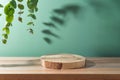 Empty wooden podium log on table with eucalyptus leaves and shadows over green background. Cosmetic mock up for design and product