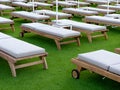 Empty wooden sun beds on a green carpet