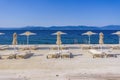 Empty wooden sunbathing deck with chairs and umbrellas by a calm blue sea under the bright sun in summer