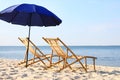 Empty wooden sunbeds and umbrella on sandy shore. Beach Royalty Free Stock Photo