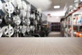 Empty wooden surface and blurred view of car tires in auto store. Space for text