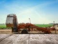 Empty wooden surface and blurred view of agricultural equipment in field. Space for text Royalty Free Stock Photo