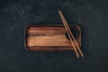 Empty wooden sushi plate with chopsticks on dark black stone background Royalty Free Stock Photo