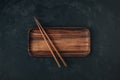 Empty wooden sushi plate with chopsticks on dark black stone background Royalty Free Stock Photo