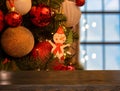 Empty wooden table on background of Christmas tree with gold, red, white balls,christmas toy in the form of a snowman and window. Royalty Free Stock Photo