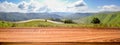 Empty wooden table with blurred panoramic background of summer landscape with road and mountain village for display or montage Royalty Free Stock Photo