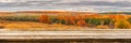 Empty wooden table with blurred picturesque autumn landscape of panoramic view from hill to lowland with field and grove in cloudy