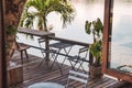 Empty wooden table and chairs on patio in tropical garden by the lake Royalty Free Stock Photo