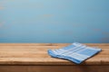 Empty wooden table with checked blue tablecloth over rustic painted wall