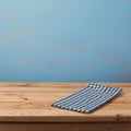 Empty wooden table with checked blue tablecloth over rustic painted wall