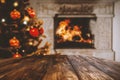 Empty wooden table with christmas tree, home interior with fireplace and dark wall background. Empty space for your products. Royalty Free Stock Photo