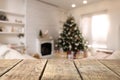 Empty wooden table in festively decorated room with Christmas tree near fireplace. Space for design Royalty Free Stock Photo