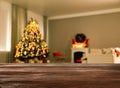 Empty wooden table in festively decorated room with Christmas tree near fireplace. Space for design Royalty Free Stock Photo