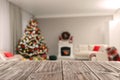 Empty wooden table in festively decorated room with Christmas tree near fireplace. Space for design Royalty Free Stock Photo